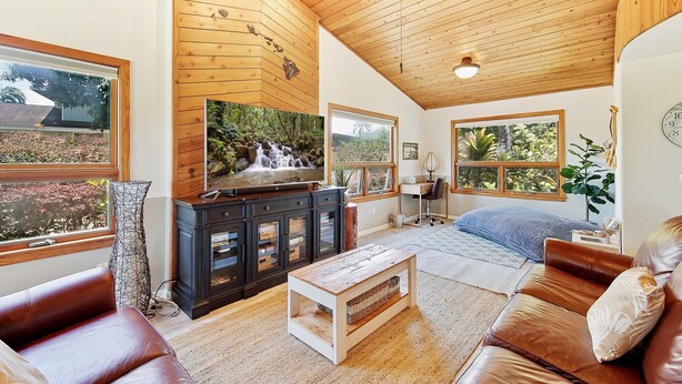 Amplia sala de estar con techo de madera, televisor, chimenea y ventanas grandes.