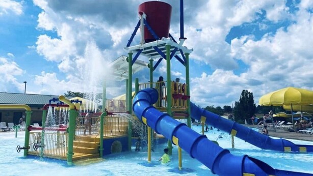 A water park with a water slide, a water play structure, and a pool. - Dewey Cottage - Central to All of SEMO Adventures (Farmington)