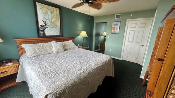 A hotel room with a large bed, a ceiling fan, a map on the wall, a door, and a nightstand with a lamp. - Lovers Key Resort Suite 5 - Bay View (Bonita Springs)