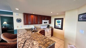 A kitchen with wooden cabinets, a microwave, stove, and granite countertops. - Lovers Key Resort Suite 5 - Bay View (Bonita Springs)