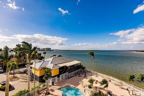 A waterfront property with a pool, outdoor seating, and a building with a sloped roof. - Lovers Key Resort Suite 5 - Bay View (Bonita Springs)