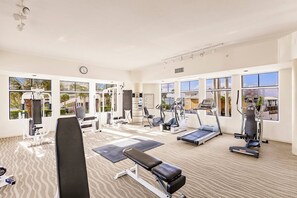 A gym with various exercise equipment, large windows, and a clock on the wall. - Lovers Key Resort Suite 5 - Bay View (Bonita Springs)