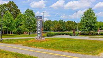 A sign for Bill Cooke Park with a clear sky and trees in the background.
