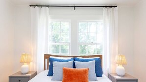 Un dormitorio con una cama grande, dos mesitas de noche y una ventana con cortinas.