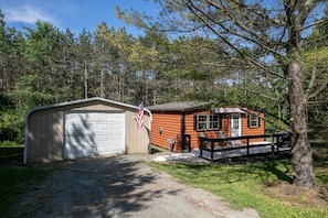 A cabin with a garage, a porch, and a flag. - Pine Ridge Cabin: an all-seasons Wellsboro getaway (Charleston Township)