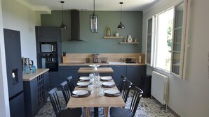 A modern kitchen with a dining table set for six, a built-in oven, and a window providing natural light.