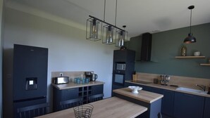 A modern kitchen with dark cabinetry, a wooden countertop, and hanging pendant lights.