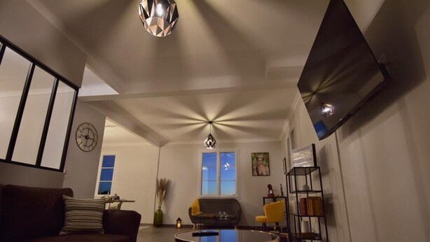 A living room with a sofa, a coffee table, and a bookshelf. There is a window with a view of the outside.