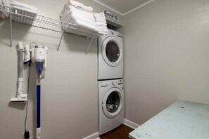 A laundry room with a stacked washer and dryer, a drying rack, and a water filtration system.