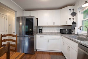 A kitchen with white cabinets, a stainless steel refrigerator, a microwave, and a coffee maker. - Mountain Getaway | Fire Pit, Mtn Scenery, Stars (Mars Hill)