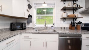 A kitchen with white cabinets, a granite countertop, a built-in microwave, a dishwasher, and a window with a view of the outdoors. - 4 BR ~ 4 Mins to Hatley Pointe ~ Fall Mtn Views (Mars Hill)
