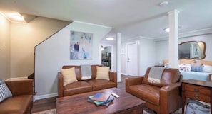 A living room with a brown leather sofa, a coffee table, and a painting on the wall. - Mountain Getaway | Fire Pit, Mtn Scenery, Stars (Mars Hill)