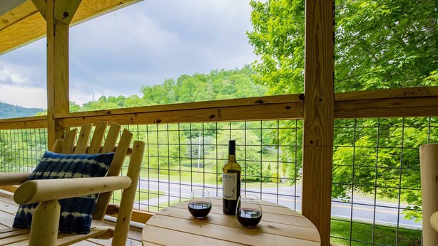 A wooden deck with a table and chairs, a bottle of wine, and two glasses. - 4 BR ~ 4 Mins to Hatley Pointe ~ Fall Mtn Views (Mars Hill)