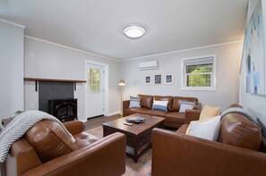 A living room with a fireplace, leather sofas, a coffee table, and a ceiling light. - Mountain Getaway | Fire Pit, Mtn Scenery, Stars (Mars Hill)