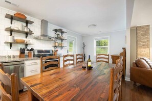 A kitchen with a wooden dining table, chairs, and a wine bottle. - Mountain Getaway | Fire Pit, Mtn Scenery, Stars (Mars Hill)