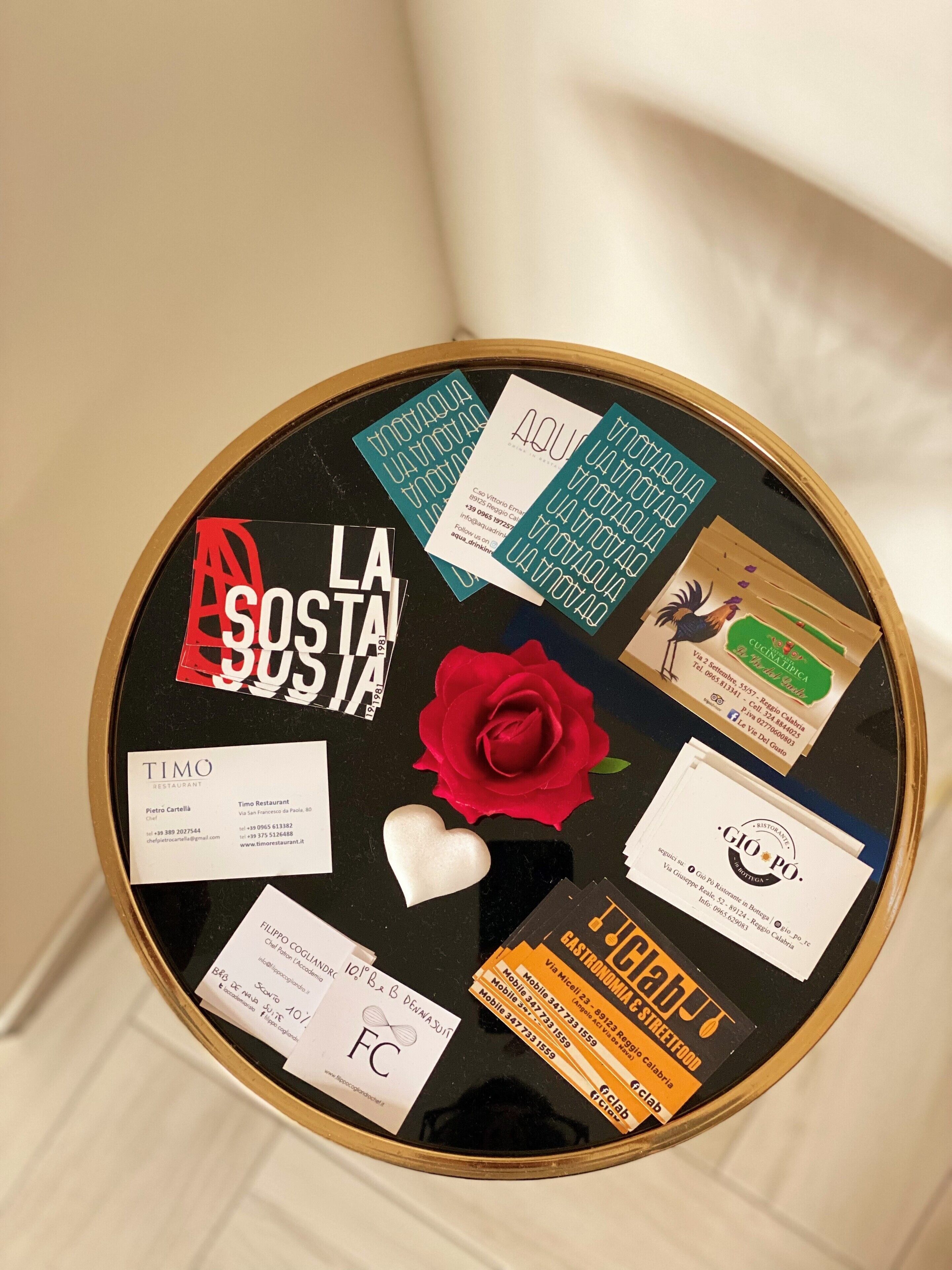 A bulletin board with various business cards and a red rose pinned to it.