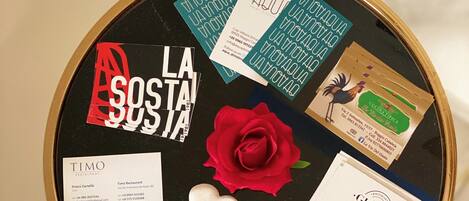 A bulletin board with various business cards and a red rose pinned to it.