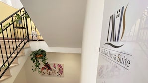 Una escalera con barandilla, una planta en maceta y una pared con un mural floral.