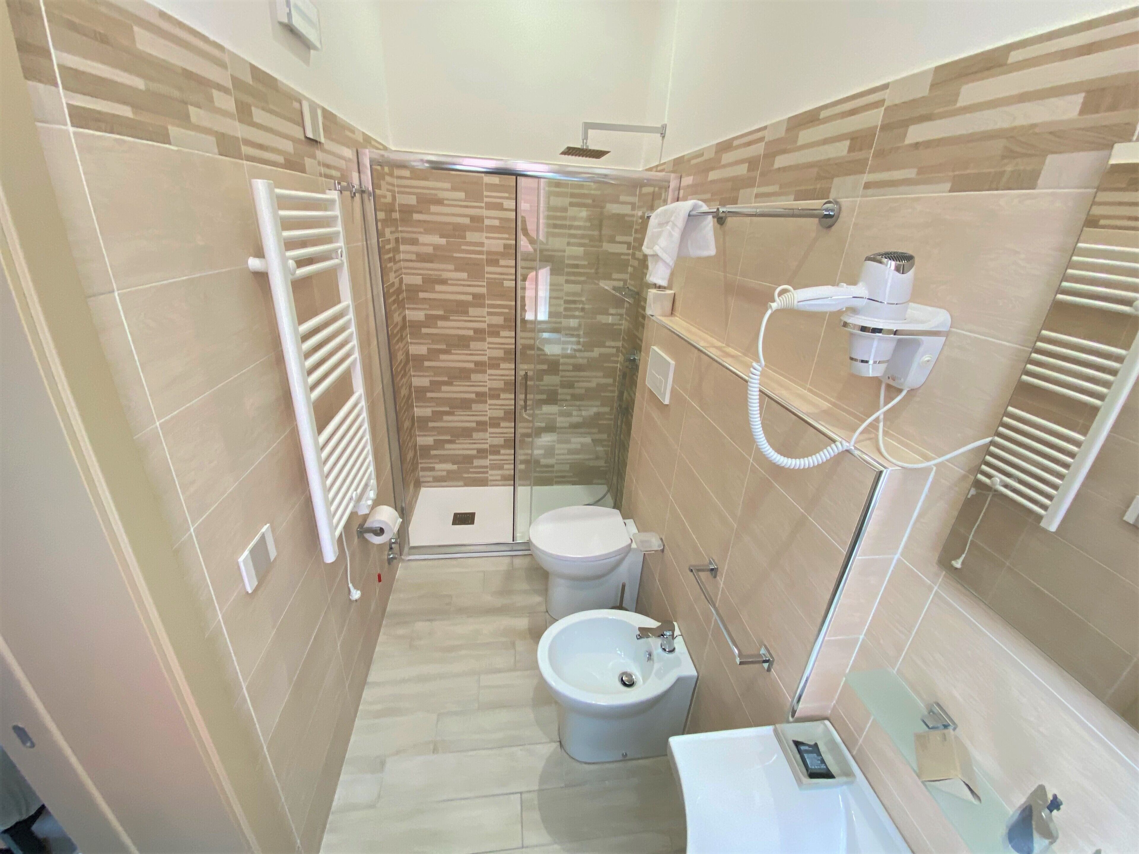 Un baño moderno con cabina de ducha de vidrio, inodoro, bidé y lavamanos con espejo.