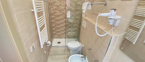 Un baño moderno con cabina de ducha de vidrio, inodoro, bidé y lavamanos con espejo.