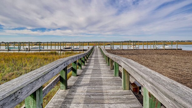 A wooden boardwalk leading to a marina with boats. - Cordgrass Bay 2315-E (Wrightsville Beach)
