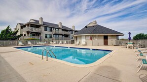 A swimming pool with lounge chairs and a building with balconies. - Cordgrass Bay 2315-E (Wrightsville Beach)