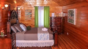 A cozy attic bedroom with a sloped ceiling, a bed with a lace bedspread, a dresser, and a nightstand.
