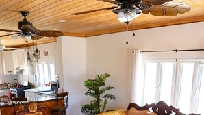 A spacious living area with a sofa, armchairs, a coffee table, and a ceiling fan.