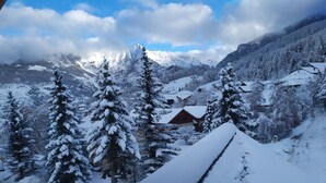 Eine verschneite Berglandschaft mit einem Chalet, umgeben von schneegefüllten Bäumen.