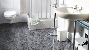 Ein Badezimmer mit Duschkabine, Toilette, Waschbecken und Spiegel.
