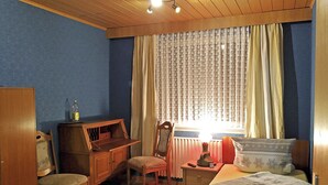 Ein Zimmer mit Bett, Schreibtisch, Stuhl und Heizkörper.