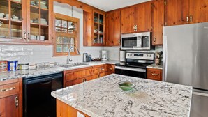 Una cocina con armarios de madera, un refrigerador de acero inoxidable, un microondas y un lavavajillas.