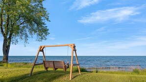 Un columpio de madera junto a una zona verde con vistas al mar.