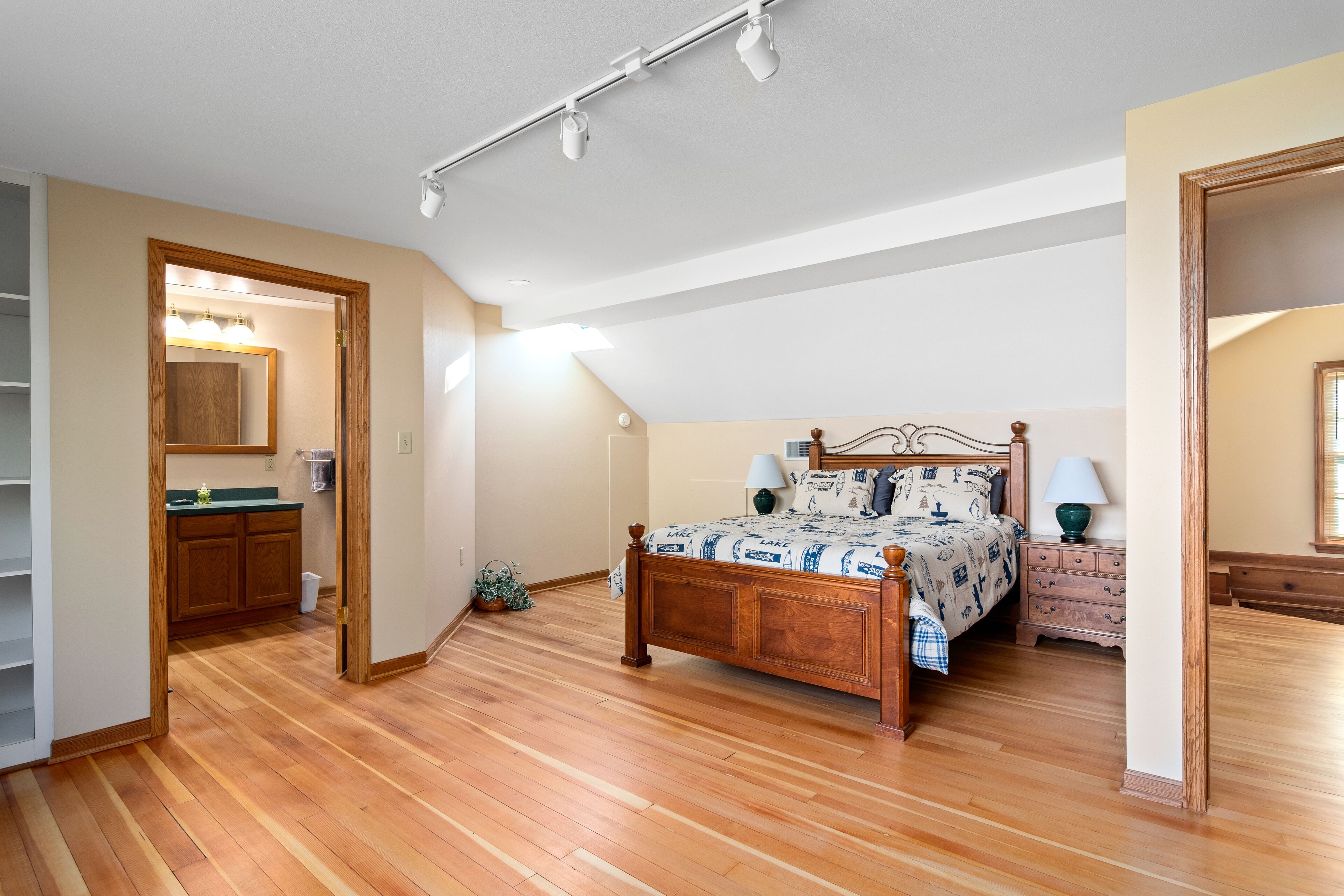 A bedroom with a wooden bed, a nightstand, a dresser, and a walk-in closet.