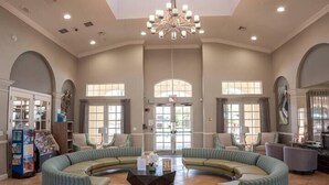 A spacious lobby with a curved seating area, a central coffee table, and large windows allowing natural light.