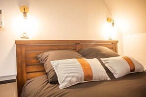 A bed with a wooden headboard, two pillows, and two wall-mounted light fixtures.