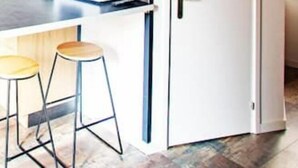 Una cocina moderna con una puerta blanca, armarios de madera y dos taburetes.