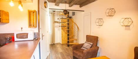 A cozy interior with a wooden staircase, a kitchen area, and seating.