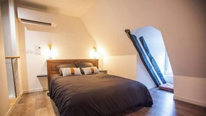 Un dormitorio con techo inclinado, una cama de madera y un banco empotrado.