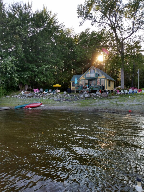 A lakeside cabin with a dock, surrounded by trees and outdoor seating. - Lakefront Cabin on beautiful Unity Pond in Burnham, Maine (Burnham)