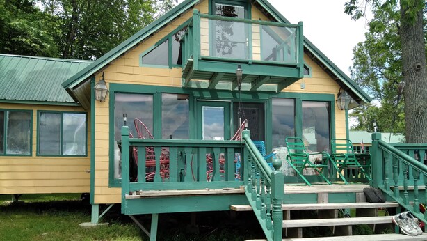 A green and yellow building with a staircase leading to a deck.