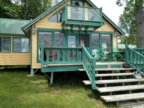 A green and yellow building with a staircase leading to a deck.