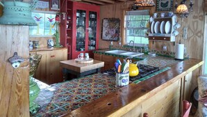 A rustic kitchen with wooden beams, a tiled backsplash, and a variety of kitchenware and decorations.