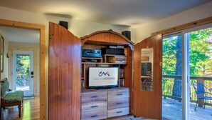 A wooden entertainment center with a flat-screen TV, built-in shelves, and drawers.