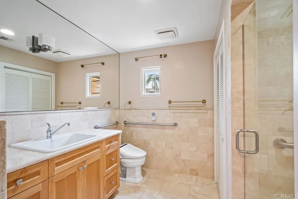 A modern bathroom with a sink, vanity, toilet, and a glass shower enclosure.