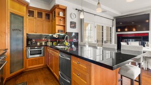 Een moderne keuken met houten kastjes, roestvrijstalen apparatuur en een zwart granieten aanrecht.