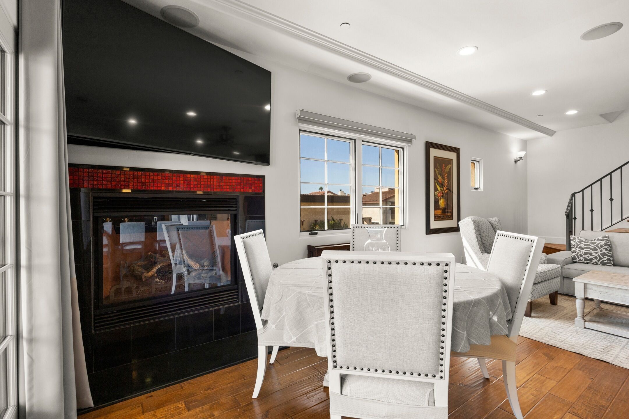 A modern living room with a fireplace, white furniture, and a staircase.