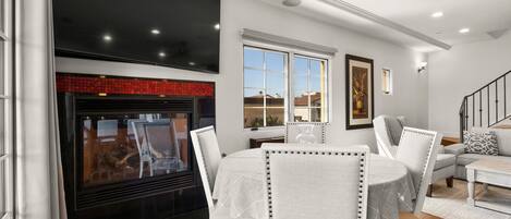 A modern living room with a fireplace, white furniture, and a staircase.