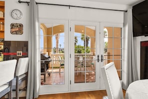 A room with a sliding glass door leading to an outdoor patio with a table and chairs. - Mandalay Shores Townhome (oxnard)