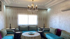 A traditional living room with a sofa set, a round coffee table, and a chandelier. - Beautiful, luxurious and very quiet apartment. (Marrakech)